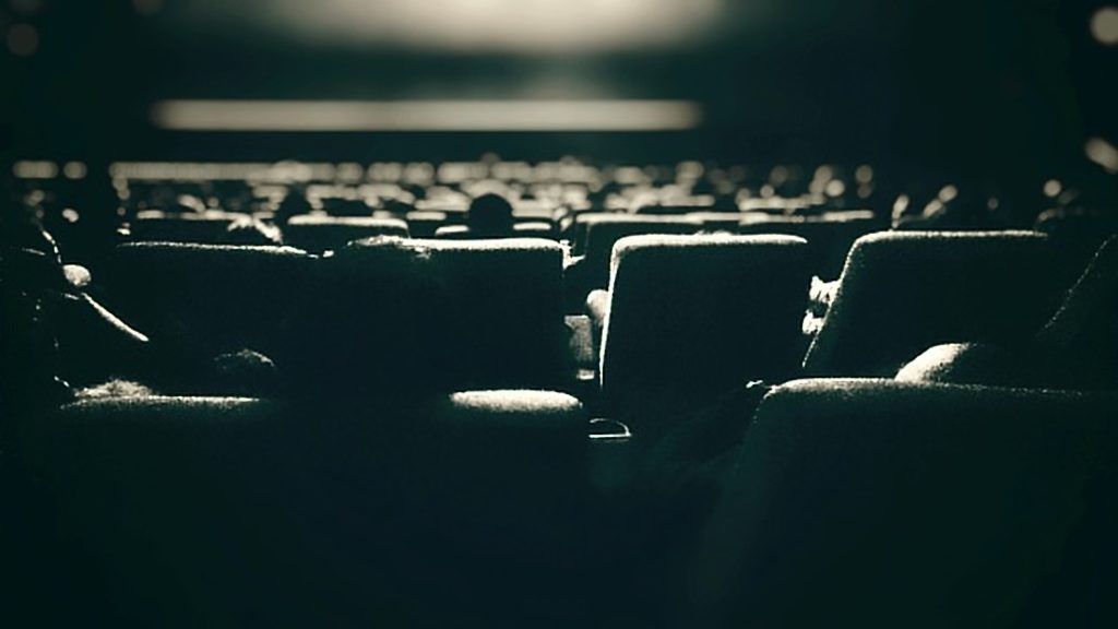 Occupied seats in a movie theater, watching trailers before the film begins