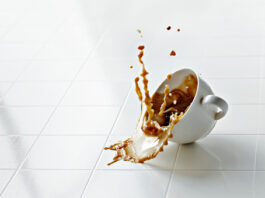 coffee cup hits white floor and spills