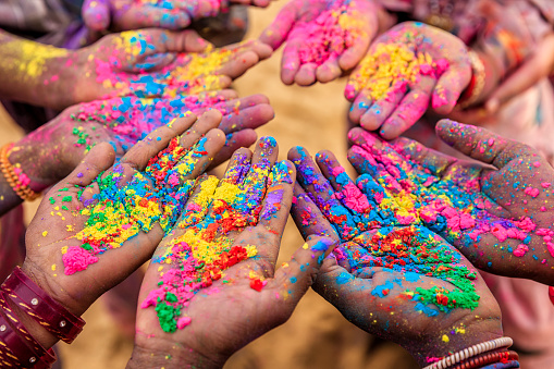 Hands holding colorful powder to celebrate Holi