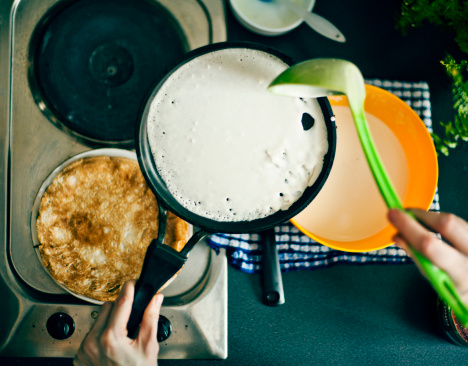 Woman making pancakes to celebrate Pancake Day