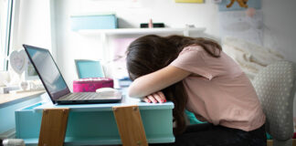 A girl face down on her desk due to stress.