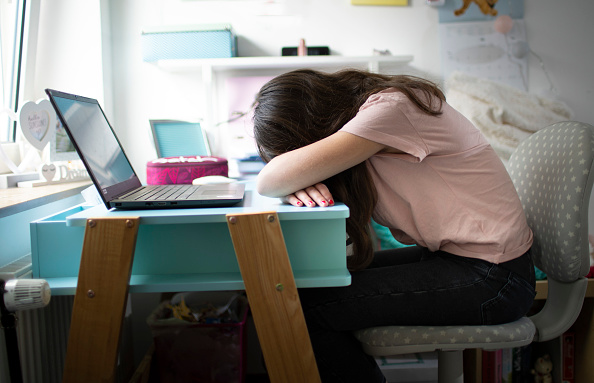 A girl face down on her desk due to stress.