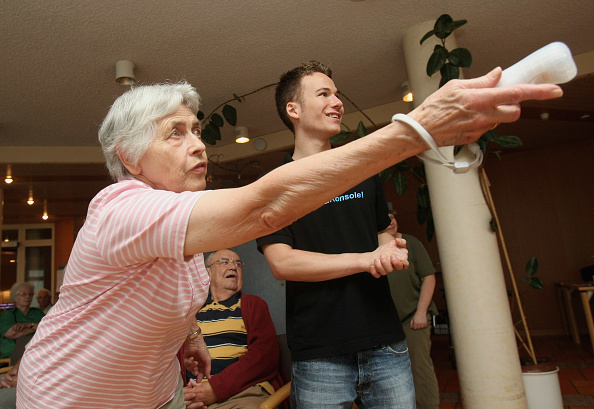 Senior citizen playing video games on Nintendo Wii.