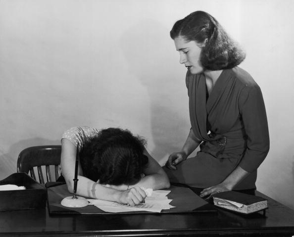 Woman face down on her desk facing a mental block.