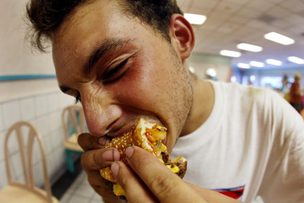 A person indulging in a burger and not practicing mindful eating.